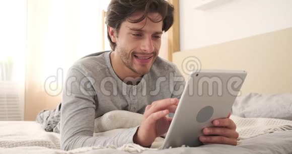 男人在床上用数字平板电脑视频的预览图