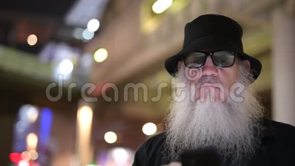 一个成熟的留胡子的游客晚上在城市的街道上探险视频的预览图