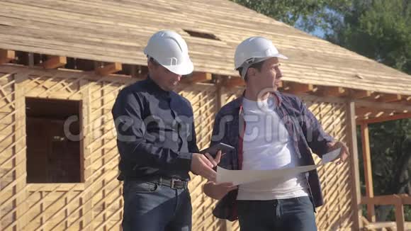 团队合作概念建筑构建建筑师慢动作视频两名戴头盔的建筑工人研究数字平板电脑视频的预览图