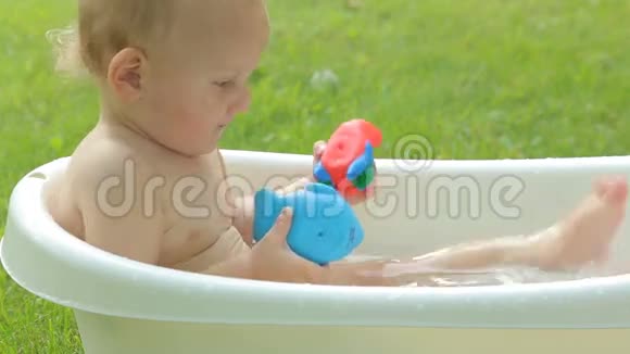 可爱的幼儿在花园里洗澡视频的预览图