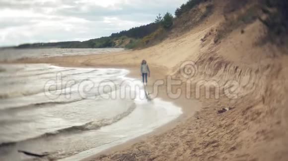 一个女人正沿着海边的沙滩散步享受生活视频的预览图