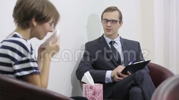 一位漂亮的男性心理医生在她探视期间看着病人视频的预览图