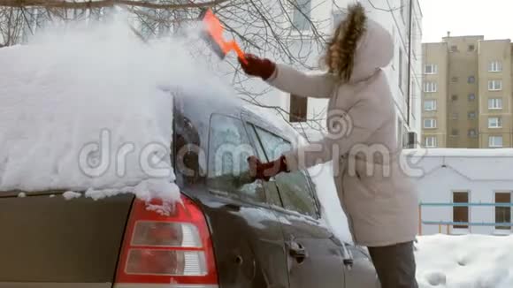 女青年在暴风雪后用刮泥机清洗汽车视频的预览图