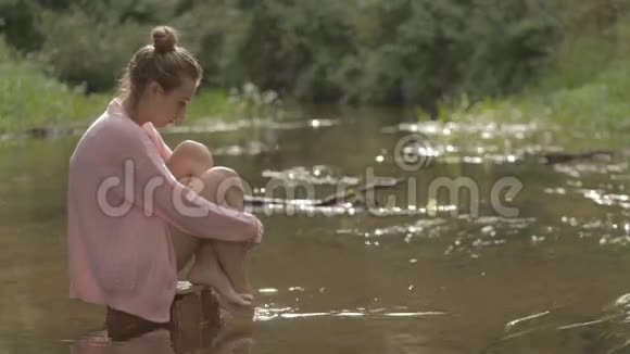 美丽的女孩在森林河的中央戏水视频的预览图