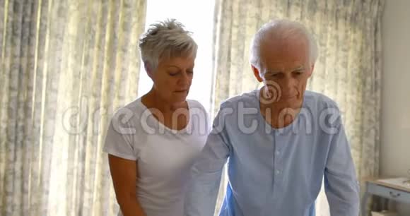 老年妇女在卧室里帮助老年男子与步行者同行视频的预览图