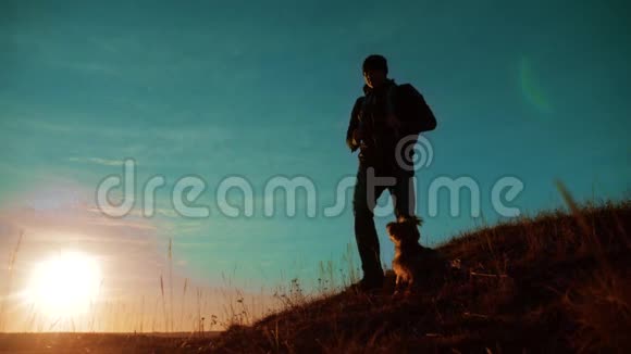 团队合作两个徒步旅行者享受日出从山顶和狗慢动作视频两个徒步旅行者视频的预览图