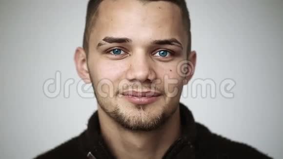 一个蓝眼睛的年轻人微笑着牙齿上戴着牙套眨眼视频的预览图