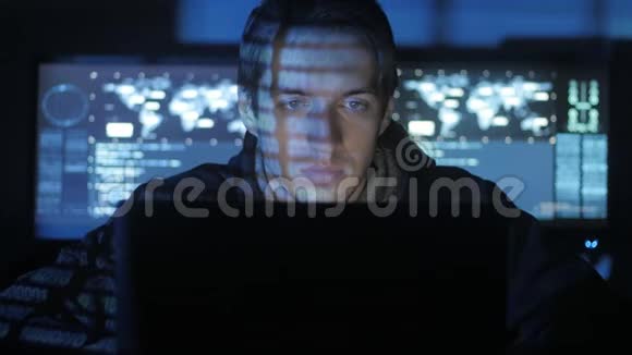 男性黑客程序员在计算机上工作而蓝码字符在网络安全中心反射他的脸视频的预览图
