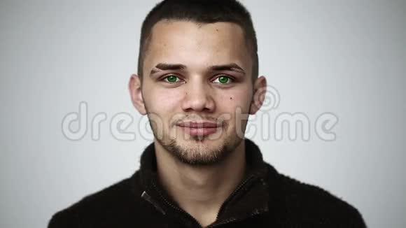 一个绿眼睛的年轻人微笑着牙齿上戴着牙套眨眼视频的预览图