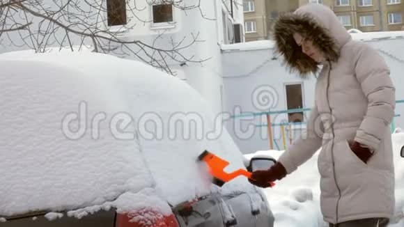 女青年在暴风雪后用刮泥机清洗汽车视频的预览图