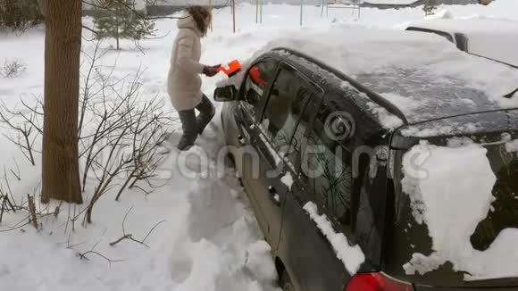 女青年在暴风雪后用刮泥机清洗汽车视频的预览图