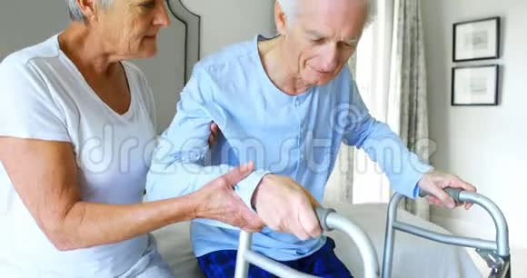 老年妇女在卧室里帮助老年男子与步行者同行视频的预览图