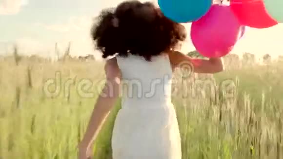 日落时分一个女孩带着彩色气球穿过麦田视频的预览图