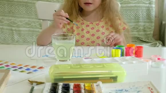 小红发姑娘坐在桌旁用颜料和画笔作画视频的预览图