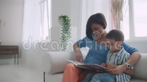 母亲和儿子坐在室内读故事视频的预览图