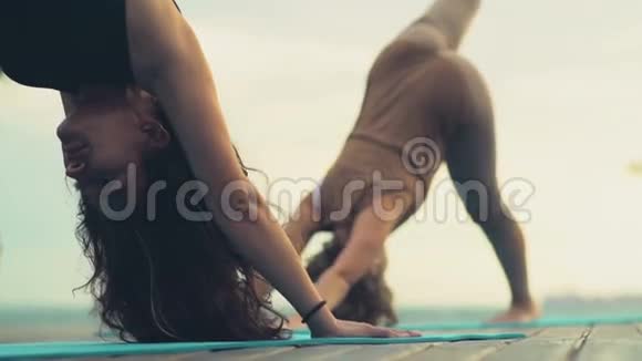两个女人在沙滩慢动作瑜伽课上视频的预览图