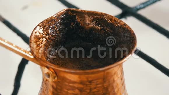 在白色煤气炉上的铜桶里煮着脱缰的黑咖啡视频的预览图