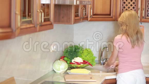 女孩洗葡萄厨房桌子上的蔬菜西红柿和卷心菜视频的预览图