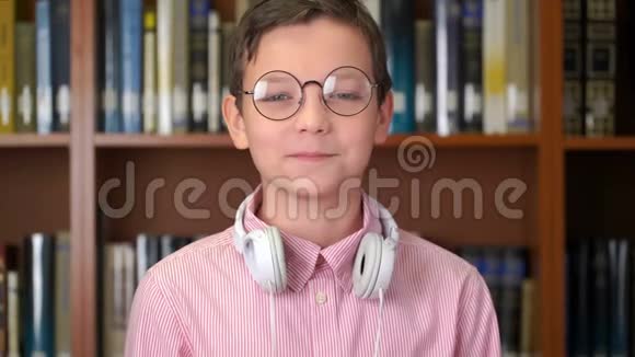 图书馆书架旁边站着一个可爱的小学生的画像视频的预览图