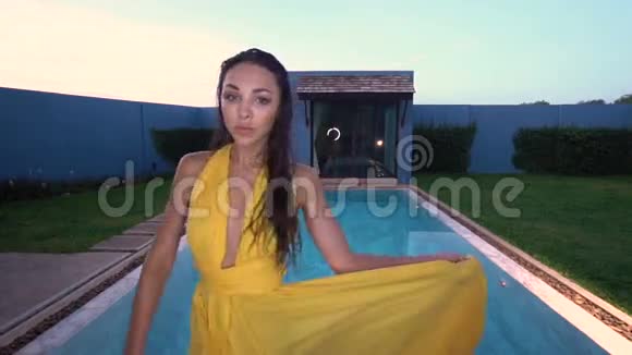 游泳池边穿着黄色连衣裙的美丽黑发女子视频的预览图