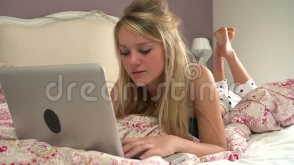 使用笔记本电脑和手机躺在床上的少女视频的预览图