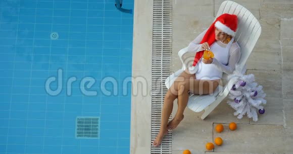 在游泳池喝鸡尾酒的圣诞快乐女人视频的预览图