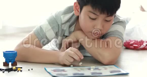 可爱的亚洲男孩在家里玩塑料块带着微笑的脸视频的预览图