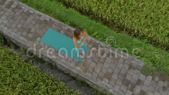 一位年轻女子在美丽的稻田上练习瑜伽的慢镜头视频的预览图