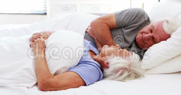 快乐的老两口在床上相互交流视频的预览图