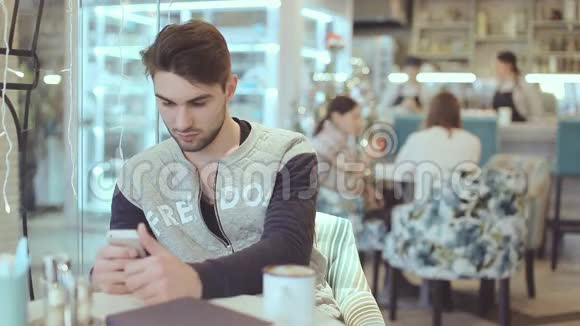 有智能手机的年轻人坐在咖啡馆里视频的预览图