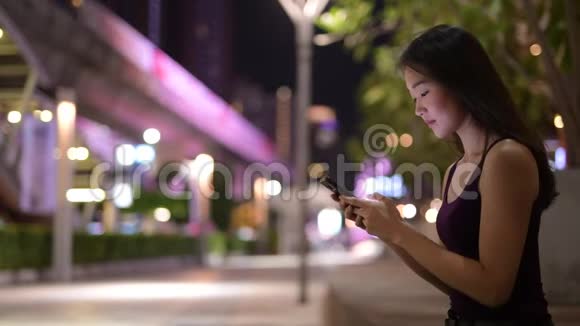晚上在户外使用手机的美丽的亚洲女人视频的预览图