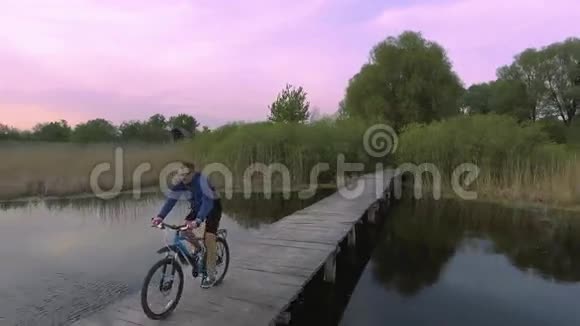 骑自行车的人骑在河对岸的木桥上视频的预览图
