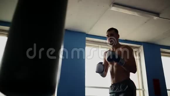 肌肉发达的男性职业拳击手训练在健身房的拳击袋裸胸手套视频的预览图
