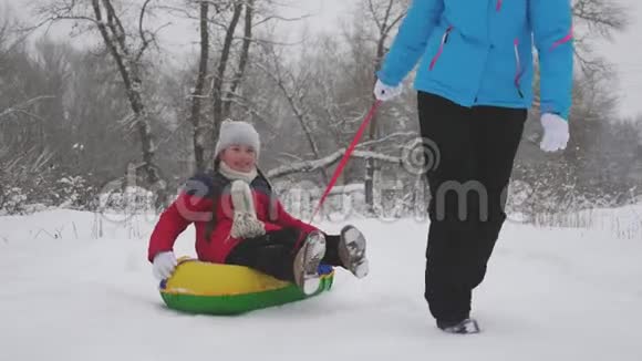 孩子和母亲在雪地里雪橇女儿和妈妈在圣诞节假期在冬季公园玩冬天视频的预览图