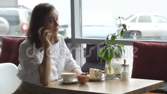 商务女性坐在咖啡馆的窗边用手机聊天视频的预览图