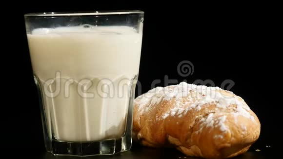 一杯牛角面包牛奶在黑色背景上旋转视频的预览图