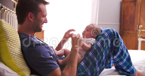 父亲在床上玩新生儿女儿视频的预览图