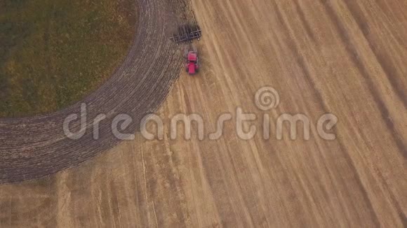 空中在耕地上向无人机射击一辆红色拖拉机在秋天开垦田地视频的预览图