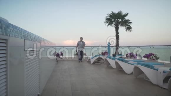 穿格子衬衫的人穿着便服在美丽的傍晚夕阳西下的屋顶上慢慢地走在玻璃窗上视频的预览图
