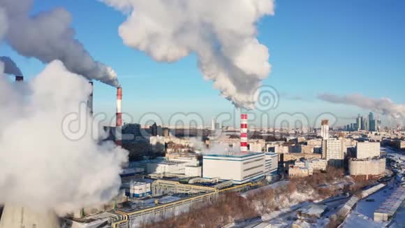 在蓝天下的冬季城市全景背景下的发电厂管道视频的预览图