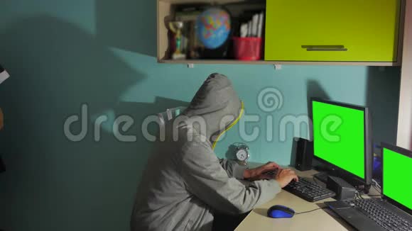 在电脑上工作的男性黑客黑客把脸藏在室内视频的预览图