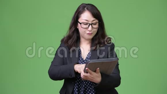成熟美丽的亚洲商人使用数码平板电脑视频的预览图