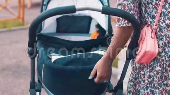 妈妈带着婴儿车在儿童操场上夏日做母亲视频的预览图