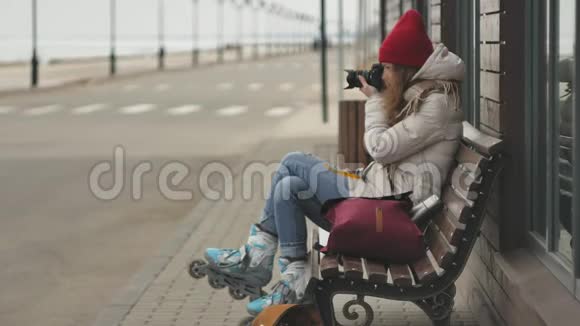 年轻漂亮的女人戴着红色帽子穿着运动温暖的衣服和滚筒坐在木凳上拿着视频的预览图