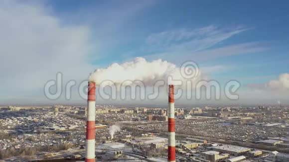 在蓝天下的冬季城市全景背景下的发电厂管道视频的预览图