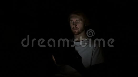 红发男子在夜间工作平板电脑视频的预览图