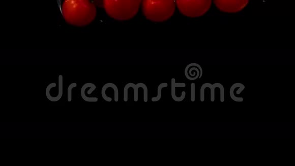 樱桃番茄落在黑色背景的水里视频的预览图
