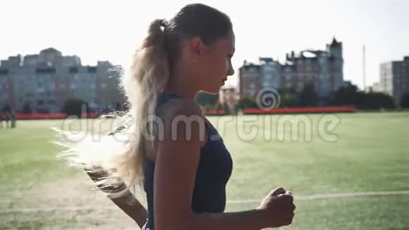 在体育场阳光明媚的早晨跑步的年轻女子视频的预览图