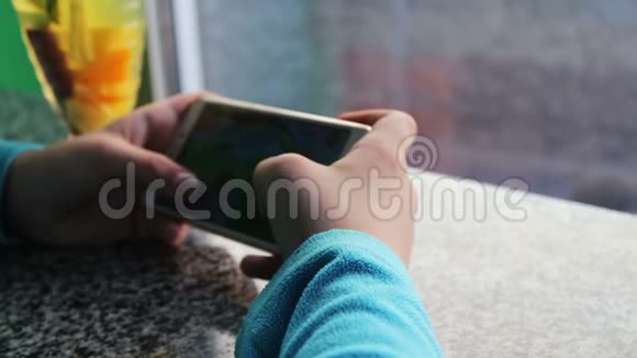 青少年在咖啡屋玩智能手机游戏旁边是柠檬茶和肉桂视频的预览图