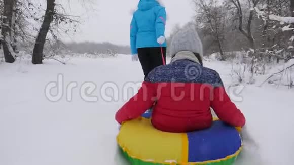 孩子和母亲在雪地里雪橇女儿和妈妈在圣诞节假期在冬季公园玩冬天视频的预览图
